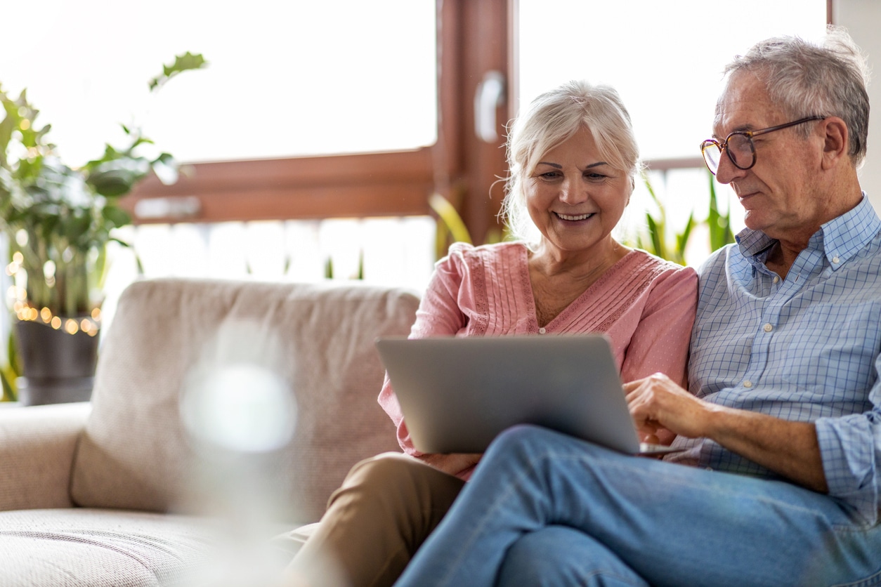 Mature couple using a laptop while relaxing at home, rebuilding trust in insurance