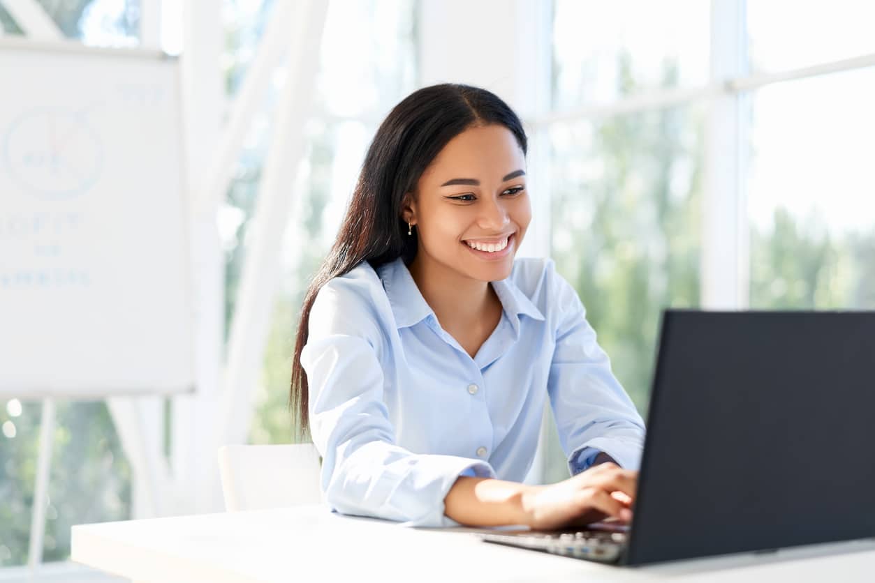 image: happy employee sitting at computer in a brightly lit office